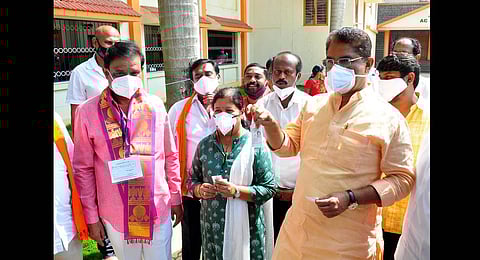 BJP candidate for RR Nagar Munirathna with Minister R Ashoka and his wife outside a polling booth in Bengaluru, on Tuesday | Express
