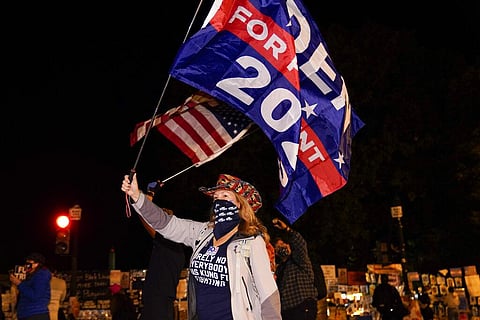 Jennifer Riggle, of Washington, waves flags in support of Democratic presidential candidate Joe Biden at Black Lives Matter Plaza, Wednesday, Nov. 4, 2020, in Washington. (Photo | AP)