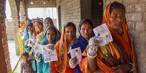 Voters display their identity cards as they stand in a queue to cast their votes during the third phase of Bihar Assembly Elections. (Photo | PTI)