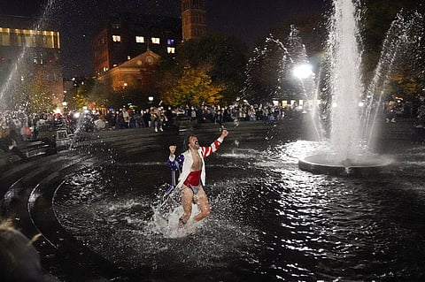 A man dances in the fountain while attending a gathering at Washington Square Park to await election results on Friday, in New York. (Photo | AP)