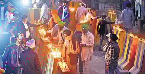Farmers light candles on the barricades blocking their entry on the occasion of birth anniversary of Guru Nanak Dev at the Singhu Border. (Photo | PTI)