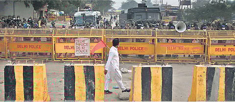 A protester walks in front of barricades as security forces look on. (Photo | Shekhar Yadav, EPS)