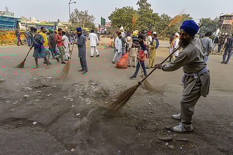 Farmers sweep roads during their 'Delhi Chalo' protest against the new farm laws, at Singhu border, in New Delhi. (Photo | PTI)