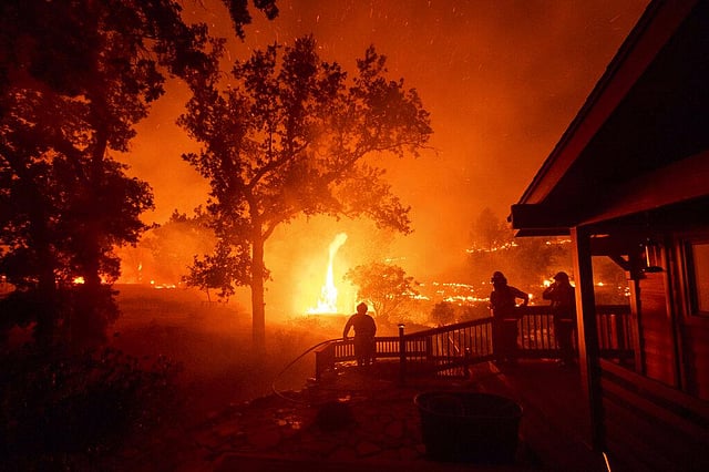 In this August 21, 2020, firefighters watch flames from the LNU Lightning Complex fires approach a home in the Berryessa Estates neighborhood of unincorporated Napa County, Calif. The blaze, the fifth largest in California history, forced thousands to flee and destroyed more than 1,000 homes and other structures. This year has seen record Atlantic hurricanes and western wildfires, devastating floods in Asia and Africa and a hot, melting Arctic. It's not just been a disastrous year, but a year of disasters. (Photo | AP)