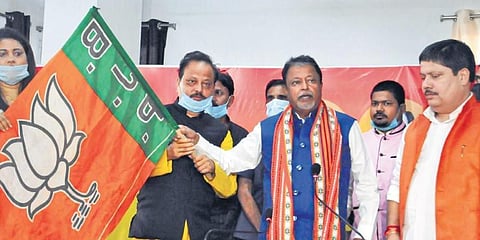 BJP national vice president Mukul Roy (2R) handovers the party flag to former TMC leaders S K Harun Rashid (2L) and Sultana Begum (L) after they joined the party, in Kolkata on Friday.