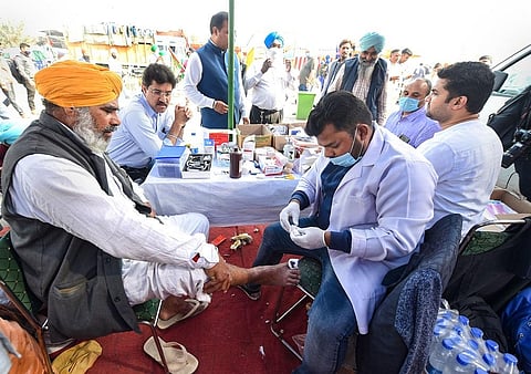 A medic provides first aid to a farmer during the 'Delhi Chalo' protest against Centre's new farm laws, at Singhu border in New Delhi. (Photo | PTI)