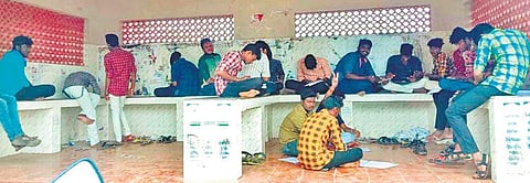 Students writing their exam at a bus stop near government arts college. (Photo| EPS)