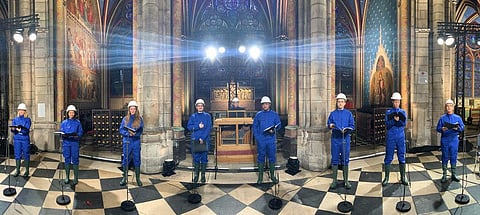 The Notre Dame Cathedral choir, wearing hard hats and protective suits, record a Christmas concert. (Photo | AP)