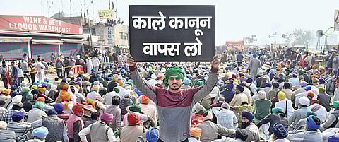 A farmer puts up a placard at the Singhu border in New Delhi on Wednesday demanding rollback of the three newly enacted central farm legislations | Parveen Negi