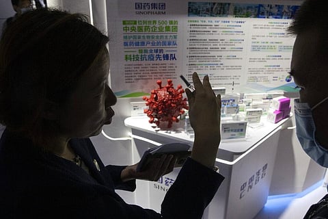 A promoter talks about the COVID-19 vaccine produced by Sinopharm subsidiary CNBG during a trade fair in Beijing. (Photo | AP)