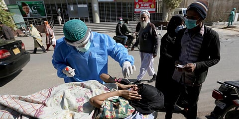 A health care worker takes a nasal swab sample from a woman at a COVID-19 testing facility at a hospital in Karachi. (Photo| AP)