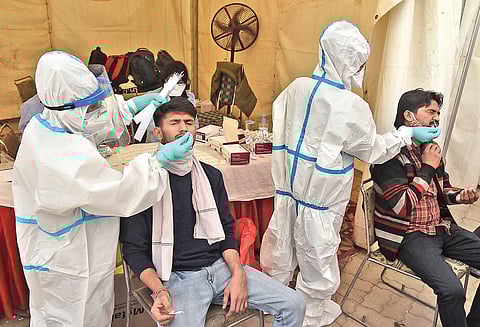 A health worker in PPE kit collects a swab sample from a man to test for coronavirus infection at ISBT Anand Vihar in New Delhi. (File Photo | Parveen Negi, EPS)