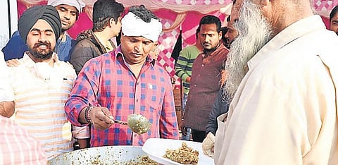 Indian Youth Congress president B V Srinivas serves food to agitating farmers as part of the langar service at the Delhi border, on Thursday | Express