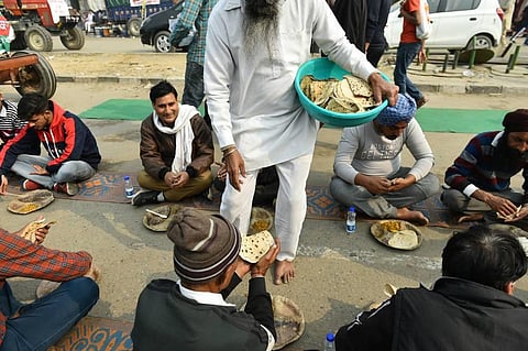 A farmer serves food to fellow farmers at Singhu border during their 'Delhi Chalo' protest against the Centre's new farm laws in New Delhi. (Photo | PTI)