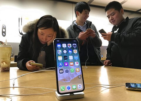 Shoppers check out smart phones at a store in Beijing. (Photo | AP)