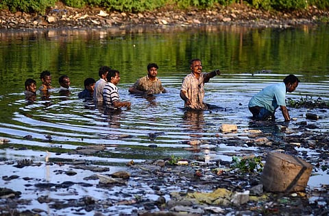 Slum dwellers standing neck-deep inside the polluted Cooum river as they protest against their eviction near Island Grounds in Chennai on Wednesday. (Photo | Debadatta Mallick, EPS)