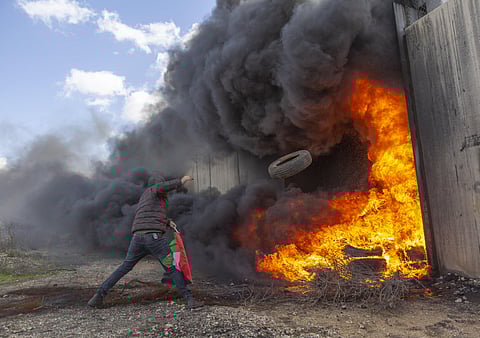 A protester burns tires by an Iron gate in the Israeli separation wall during a protest against Israel and the Untied States in the West Bank village of Bil'in, near Ramallah, Friday, Jan. 31, 2020. (Photo | AP)
