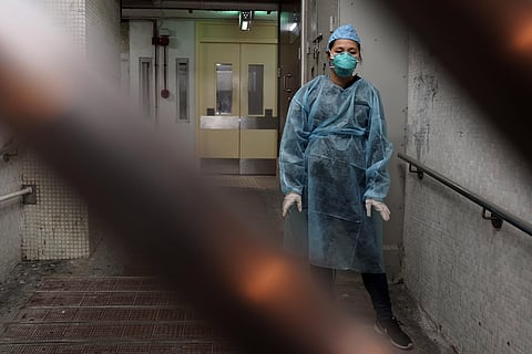 A woman wearing a protective suit waits near an entrance at the Cheung Hong Estate, a public housing estate during evacuation of residents in Hong Kong, Tuesday, Feb. 11, 2020. (Photo | AP)