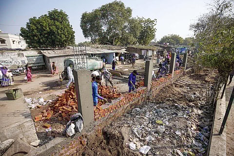 Workers construct a wall in front of a slum ahead of US President Donald Trump's visit in Ahmedabad. (Photo| PTI)