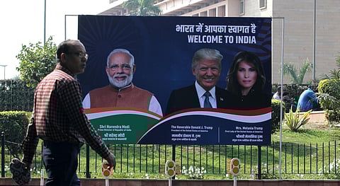 A man crosses next to a hoarding with the images of U.S. President Donald Trump and Prime Minister Narendra Modi in New Delhi on Monday. (Photo | Shekhar Yadav/EPS)