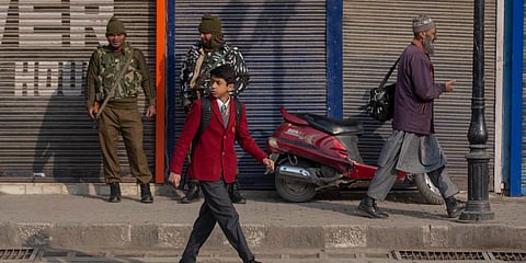 A Kashmiri schoolboy walks past soldiers outside his school in Srinagar. (Photo| AP)