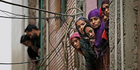 Muslim women look out of a window as security officers patrol a street in New Delhi. (Photo | AP)