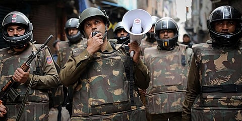 A Delhi police officer makes announcements to warn residents from venturing outside their homes as security officers patrol a street in New Delhi. (Photo | AP)