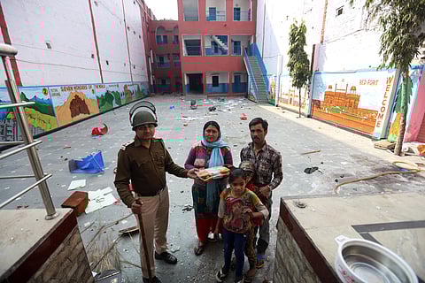 A Delhi Police sub -inspector offers his food to a school guard and his family at Rajdhani Public School at Shiv Vihar in northeast Delhi on Wednesday. (Photo | Shekhar Yadav/EPS)