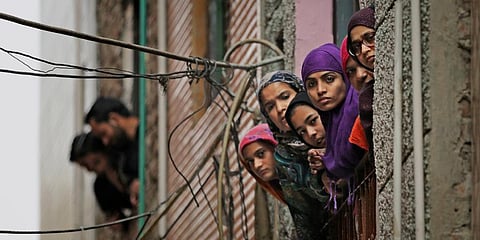 Muslim women look out of a window as security officers patrol a street in New Delhi. (Photo | AP)