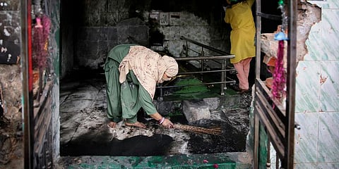 A Muslim woman cleans a shrine burnt in Tuesday's violence in New Delhi. (Photo | AP)