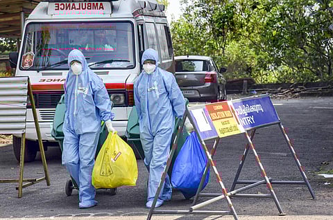 Medical staff wearing protective suits hold medical waste as they exit the Special Isolation Ward set up to provide treatment to novel coronavirus patients at Kochi Medical college. (Photo| PTI)