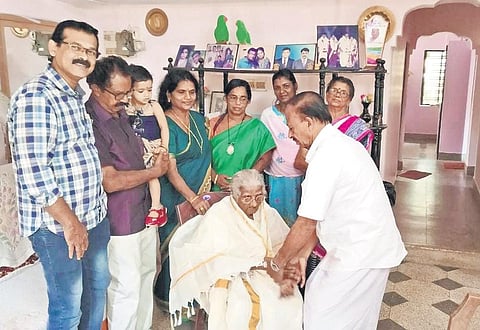 Thrikkaruva panchayat president K Chandrasekhara Pillai drapes Bhageerathi Amma with a ponnada on her success. (Photo | EPS)
