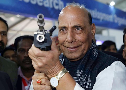 Defence Minister Rajnath Singh holds a Light Machine Gun at DRDO Pavilion during the inauguration of Defence Expo 2020 in Lucknow on Wednesday. (Photo| ANI)