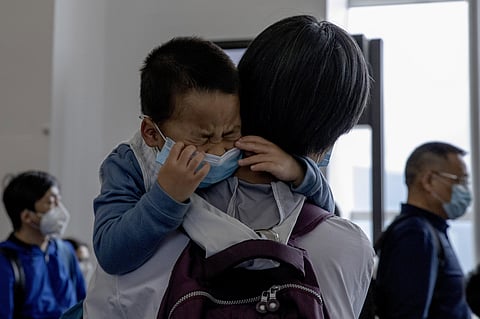 A child cries as he waits in line to board a plane for Beijing at the airport in Hong Kong. (Photo | AP)
