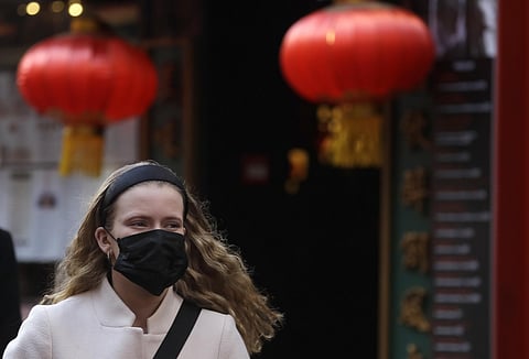 A woman wears a mask as she walks near China Town in London. (Photo | AP)