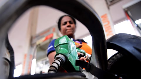 An employee at a petrol bunk fills fuel in a vehicle.