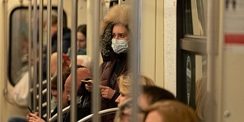 A woman wears a medical mask holds a smartphone standing inside a metro train in Moscow on Monday. (Photo| AP)