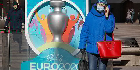 A woman wears a medical mask walks past a sign with Euro 2020 emblem in St.Petersburg where UEFA planned to host four UEFA EURO 2020 matches. (Photo| AP)
