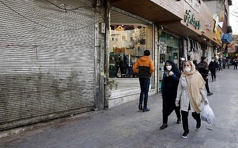 People, some wearing protective face masks, walk past shops along outside the Tajrish Bazaar in Iran's capital Tehran on March 12, 2020. (Photo | AFP)