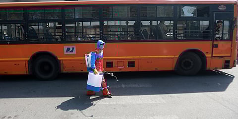 A volunteer sprays disinfectants a DTC bus in the wake of coronavirus COVID-19 pandemic at Sunehri Pul Bus Depot Lodhi Road in New Delhi. (Photo | Shekhar yadav, EPS)