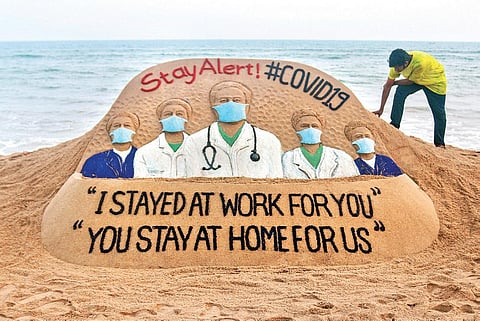 Sudarshan Patnaik creates a sand sculpture on the need for social distancing as precautionary measure for COVID-19 on Puri beach. (Photo | EPS)