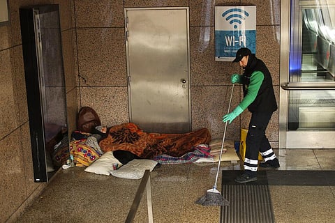 A cleaner mops next to a homeless man at the Schuman metro station during a partial lockdown ordered by Belgium government in Brussels, Monday, March 23, 2020.  (Photo | AP)
