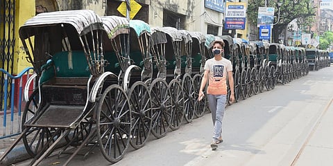 A boy wearing a mask walks past parked rickshaws alongside a street during lockdown in the wake of coronavirus outbreak, in Kolkata. (Photo| PTI)