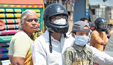 A father and his son wear masks, while the elderly woman doesn’t have one as they go on a bike. (Photo| RVK Rao, EPS)
