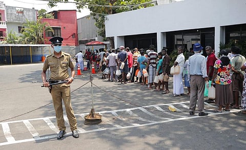 Sri Lankans queue for kerosene as a police officer stands guard during a temporary lift of a curfew as virus-containment measures in Colombo, Sri Lanka, Tuesday, March 24, 2020. (Photo | AP)