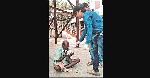 Youths distributing food to a homeless man in Sambalpur (Photo | EPS)