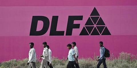 Workers walk past a billboard of DLF Ltd. at Gurgaon in the outskirts of New Delhi (File photo | Reuters)