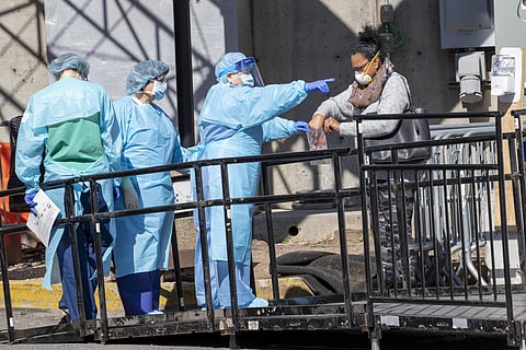 A member of the Brooklyn Hospital Center helps a person who was just tested for COVID-19 put an object in a biohazard bag, Thursday, March 26, 2020, in New York. (Photo | AP)
