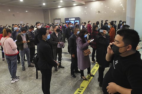 Travelers wearing masks line up to buy train tickets at a railway station in Yichang in central China's Hubei province Wednesday, March 25, 2020. (Photo | AP)