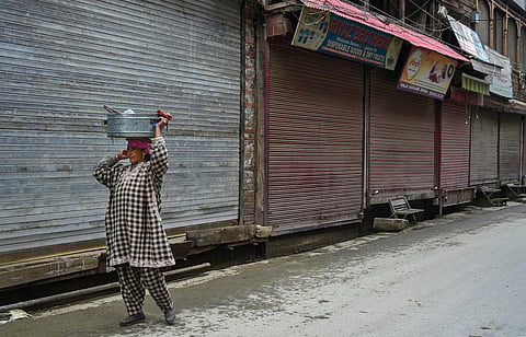 A woman sells fish near closed shops during a 21-day nationwide lockdown in the wake of coronavirus pandemic in Srinagar Wednesday March 25 2020. (Photo | PTI)